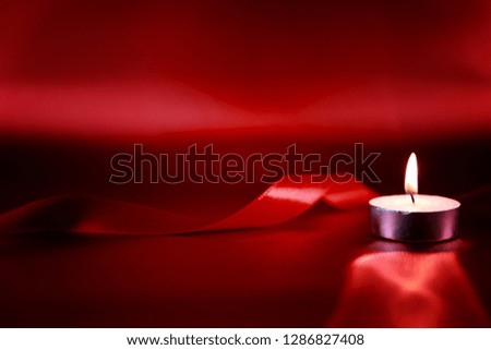 Valentine's day concept. Candle in candlestick with red ribbon on red shiny background