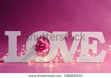 White love text wood and led light with pink rose on wooden background. Valentine concept.