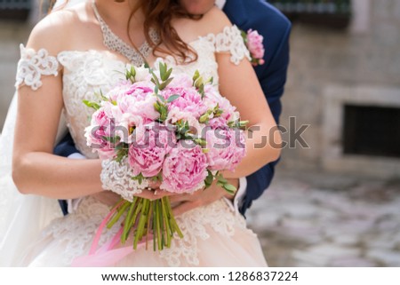 wedding bouquet of pink peonies in the hands of the bride