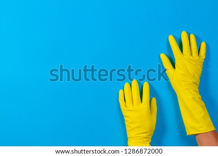 Hands in yellow gloves on blue background