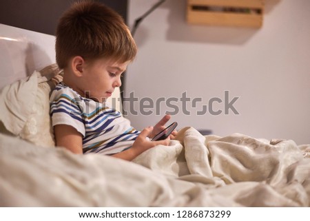 boy watching a cartoon on the phone in bed