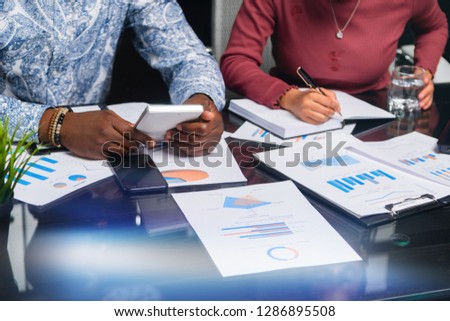 hands of dark-skinned people hold calculator against background of financial documents in business space closeup