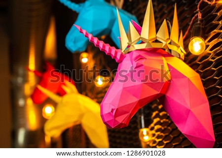 Pink and colorful  paper unicorn on dark background. Origami toy. Origami pegasus. Head of unicorn of paper.