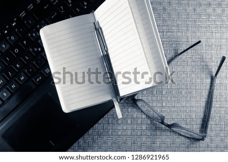 Agenda with blank pages open and resting on the keyboard of a notebook, monochrome interpretation of the shot.