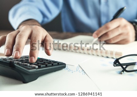 Businessman using calculator in his desk. 