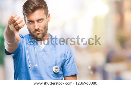 Young handsome doctor surgeon man over isolated background looking unhappy and angry showing rejection and negative with thumbs down gesture. Bad expression.