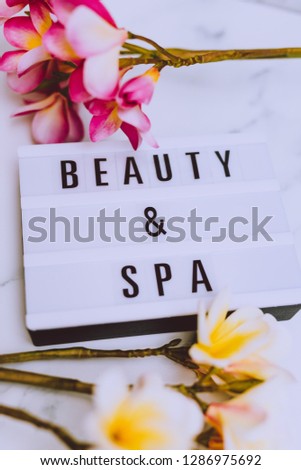 beauty and spa lightbox text surrounded by tropical frangipani monoi flowers