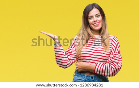 Young beautiful woman casual stripes winter sweater over isolated background smiling cheerful presenting and pointing with palm of hand looking at the camera.