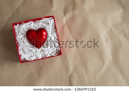 Red gift box with heart by Valentine's day on craft paper. Giving heart love concept, copy space