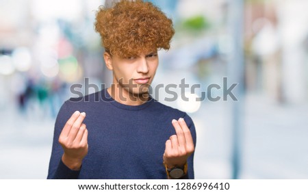 Young handsome man with afro hair Doing money gesture with hand, asking for salary payment, millionaire business