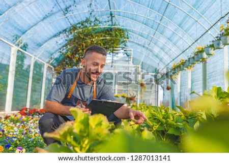 Loving gardening. Shot of a happy male florist in his garden center.  Portrait of beautiful young guy in the hothouse taking care of flowers. 