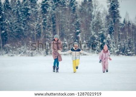 Happy family of mother and kids having fun outdoors in winter