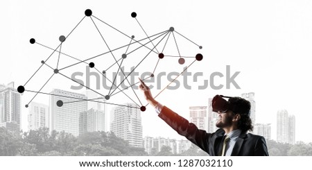 Young businessman in virtual helmet against cityscape background touching social connection concept. 3d rendering