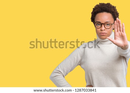 Young beautiful african american woman wearing glasses over isolated background doing stop sing with palm of the hand. Warning expression with negative and serious gesture on the face.