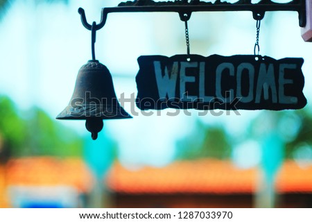 blurred welcome signage with old metal bell on blurred background