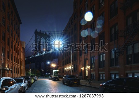 Brooklyn bridge seen from a narrow alley enclosed by two brick buildings at dusk, NYC USA