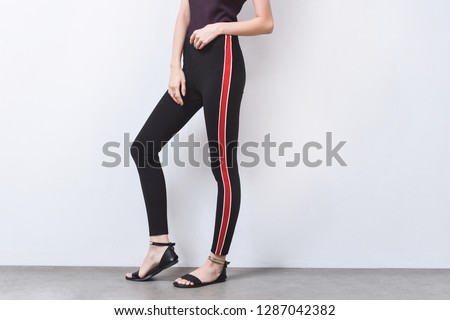 womans in black and red striped pants and black high hell shoes on gray background
