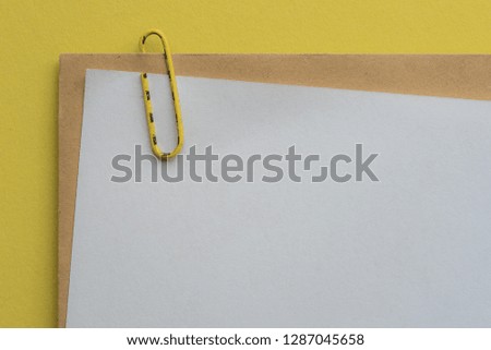 Empty letter as placeholder with an envelope attached with a paperclip before yellow background