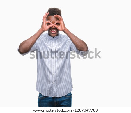 Young african american man over isolated background doing ok gesture like binoculars sticking tongue out, eyes looking through fingers. Crazy expression.