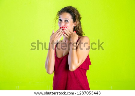 Close-up photo of surprised pretty young woman with opened mouth, touching her cheek, looking at camera
