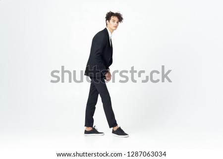 Cute business man in a dark suit in full growth on a gray background