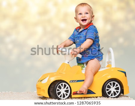 Little boy having fun on yellow toy car