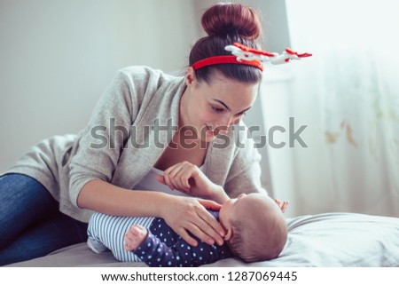 Young mother playing with her baby girl. Mother playing with baby on bad.