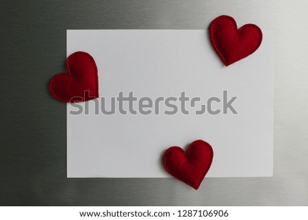 Handmade red felt heart shape magnets on refrigerator door. White kitchen on background. Diy valentines day decoration for home. Place for text