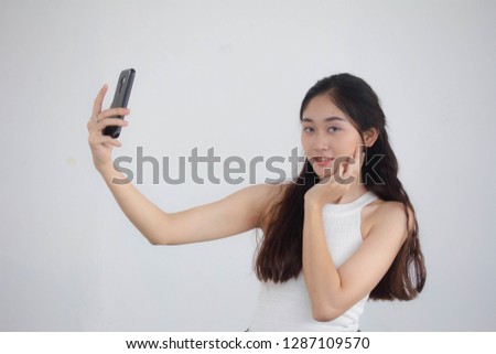 Portrait of thai china adult beautiful girl White shirt blue jeans using her smart phone Selfie