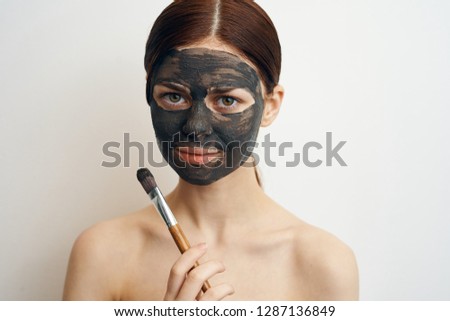 young woman in a cosmetic mask made of clay care