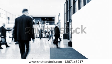 unrecognizable business people walking at a trade show with banner 