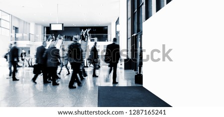 crowd of anonymous blurred people at a trade show, with banner and copy space for individual text 