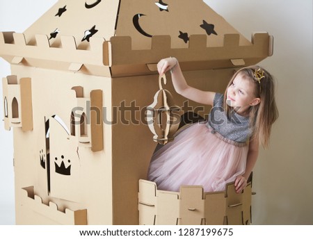 Beautiful little girl in princess dress playing with her toy castle.