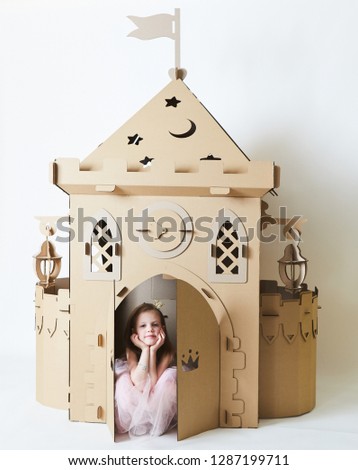 Beautiful little girl in princess dress playing with her toy castle.