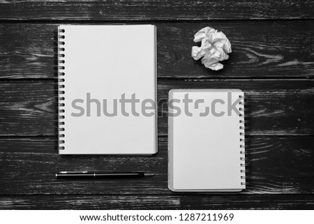 Notebook, pen and  crumpled sheet of paper  on black desk background. Business and learning concept. Black and white photography
