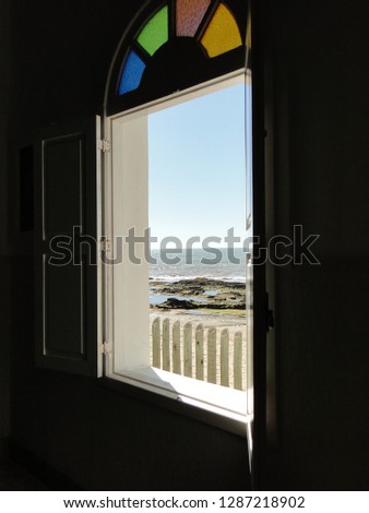 view from inside a church to the sea, deep blue,with stylized glasses in blue, green, red and green