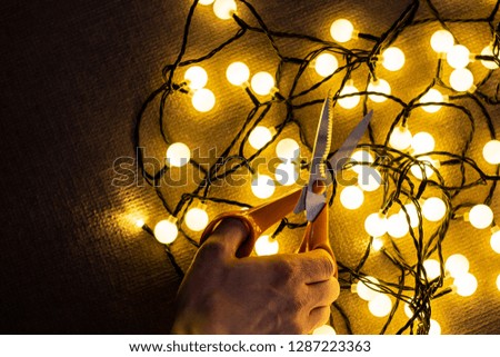Christmas lights on floor and hand with cutting scissors