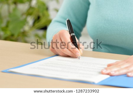 Close up front view portrait of a hand signing a contract on a desktop at office