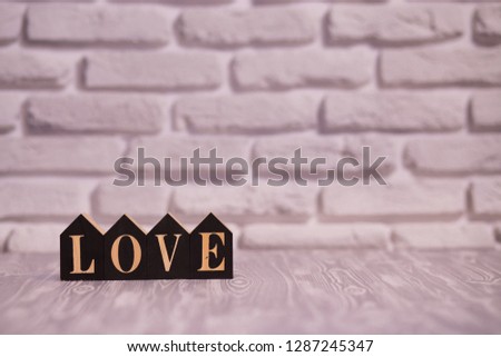 Text love on black wooden blocks with white brick background.