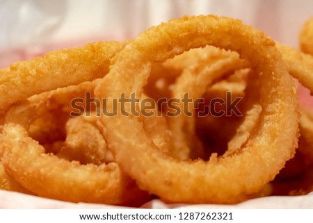 Close up view of deep friend  golden onion rings in a basket with white paper liner.