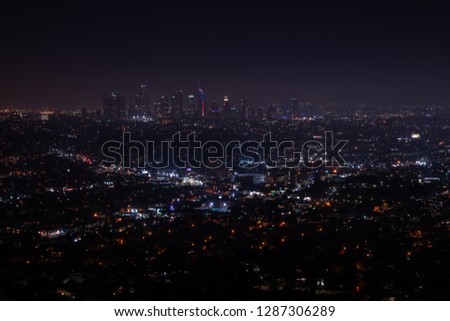 Beautiful super wide-angle night aerial view of Los Angeles, California, USA, with downtown district and mountains with sky full of stars and milky way, seen from the Griffith Park observatory.