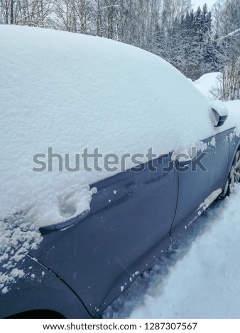 Snow covered car on a winter morning. Snow blizzard during the night. Icy vehicle.