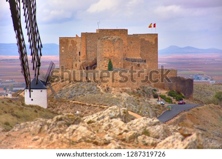 CONSUEGRA, SPAIN - NOVEMBER 22, 2018: Windmills of Don Quixote route, View of the medieval castle of the city of Castilla La Mancha in the background.