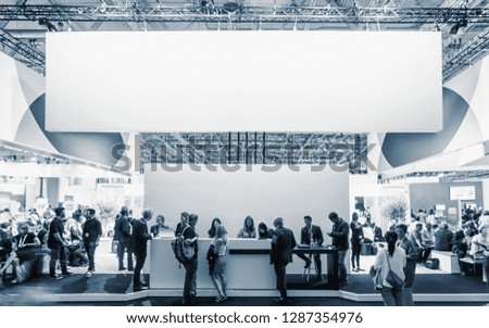 business people walking between trade show booths at a public event exhibition hall, with banner and copy space for individual text Royalty-Free Stock Photo #1287354976