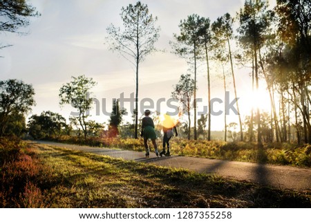 Two women doing roller skating in the forest