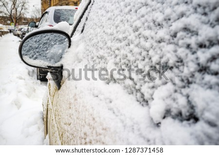 car covered with snow and a rearview mirror close-up with a large free space