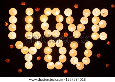 Words I LOVE YOU formed by glowing candles and decorated with flowers. Greeting to St. Valentine's Day.