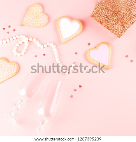 Happy Valentine's day greeting card with heart cookies, wine glasses and wine on pastel pink background.