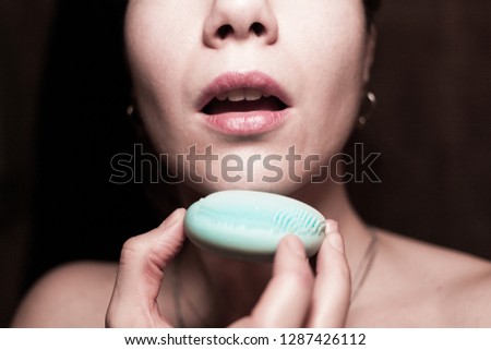 Closeup of a beautiful young woman cleaning her face with a sonic facial brush