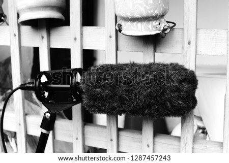 Boom leant against a wooden fence. Equipment used to record sound for film or television production.
